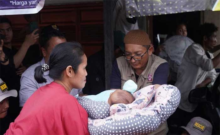 Wali Kota Padang membantu seorang bayi korban banjir.