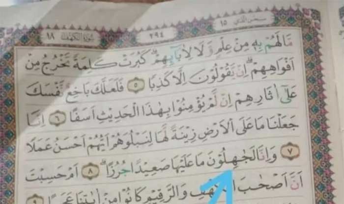 Panah biru menunjukkan Mushaf Alquran salah cetak.