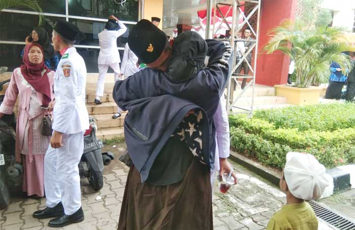 Wia Leni Lestari memeluk erat anak kesayangannya Ilham Wihen S, sesaat setelah Ilham menyelesaikan tugas mulia pengibaran bendera di halaman Kantor Bupati Agam, Padang Baru, Lubuk Basung, Kamis, 17 Agustus 2023.