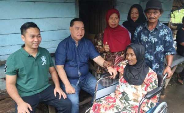 Bupati Halikinnor saat menyerahkan kursi roda kepada warga yang membutuhkannya. (ist)