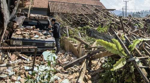 Warga melintas di dekat rumah yang rusak pascagempa bumi di Desa Cibeureum, Kertasari, Kabupaten Bandung, Jawa Barat, Rabu (18/9/2024). (ANTARA FOTO/NOVRIAN ARBI/detikjabar.com)