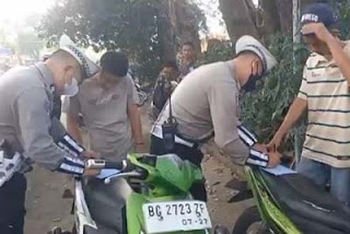 Polisi menilang pengendara motor yang melanggar aturan lalu lintas dalam Operasi Patuh.
