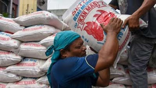 Pekerja memanggul karung berisi beras saat bongkar muat di Pasar