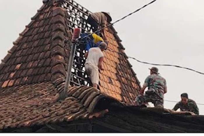 Warga dibantu anggota TNI bergotong royong memperbaiki rumah warga.