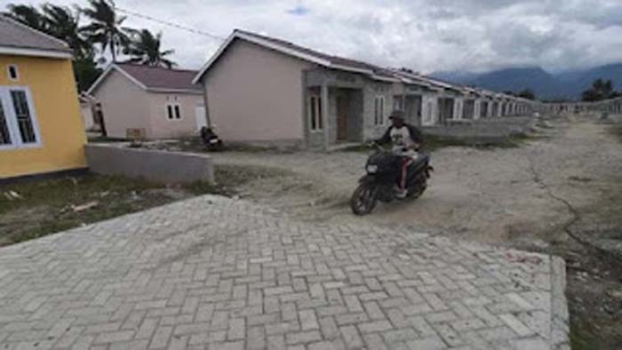 Pekerja melintas di sekitar proyek pembangunan perumahan bersubsidi di Kabupaten Sigi.